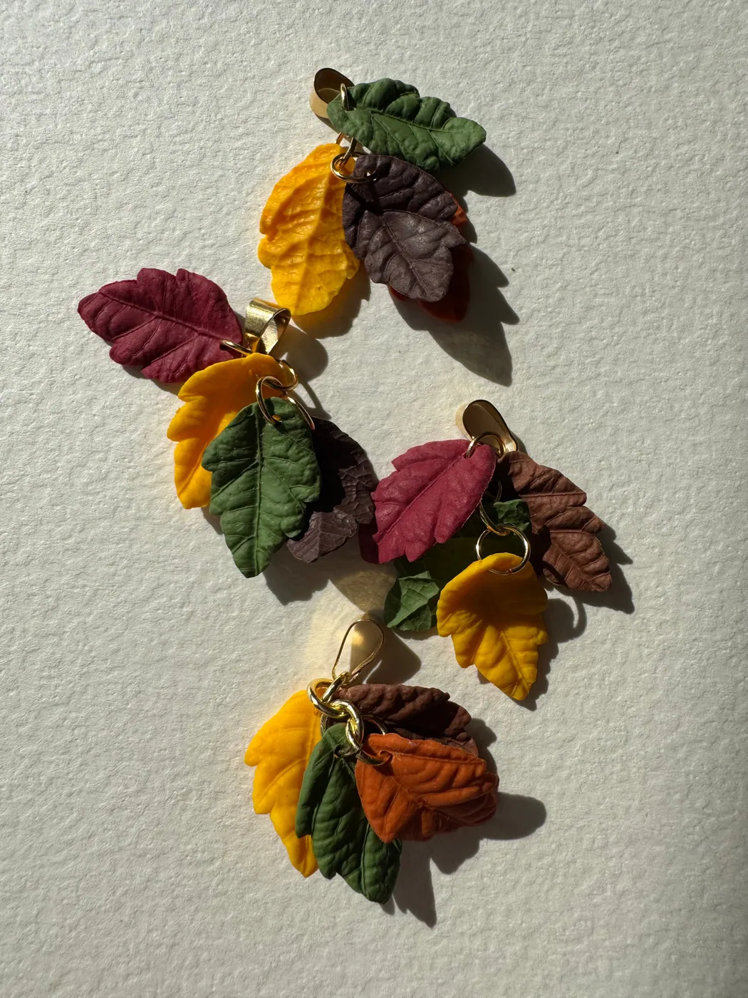 Hand-sculpted autumn leaf pendants on paper